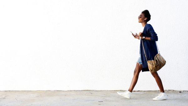 Young businesswoman walking to work enjoying music on headphones