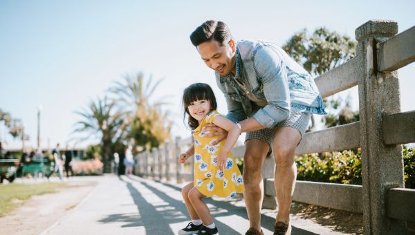 father helping young daughter skateboard