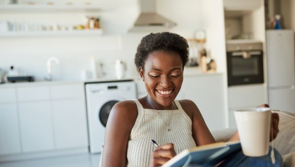 woman happily writing in notebook in kitchen