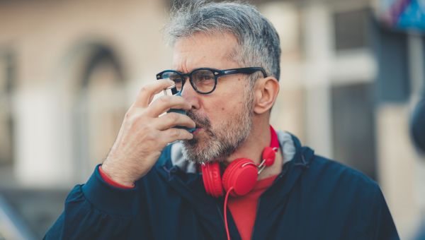 man using an inhaler for breathing trouble