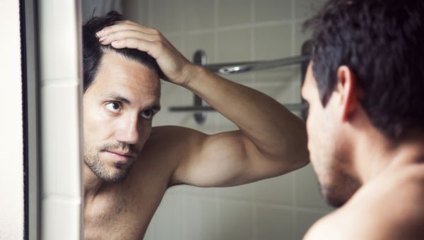 man looking at hairlines in mirror