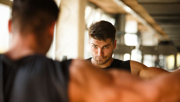 man lifting weights in mirror at gym