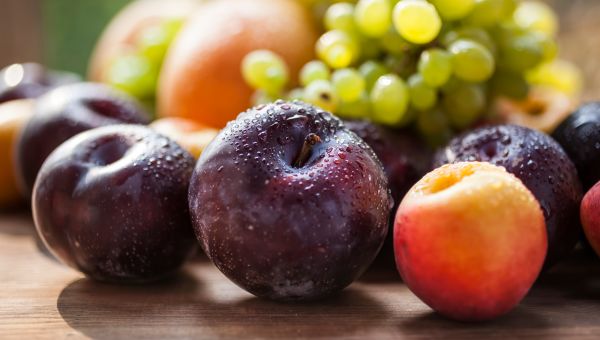 plums, grapes, and peaches laid out on a table