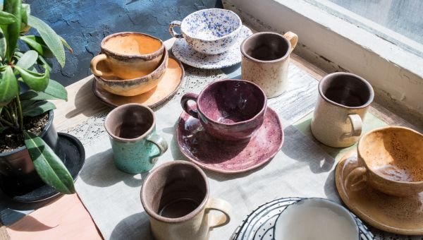 A collection of ceramic bowls and cups near a window
