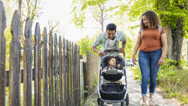 a Black man and women take their baby out for a walk in a stroller
