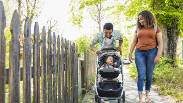 a Black man and women take their baby out for a walk in a stroller
