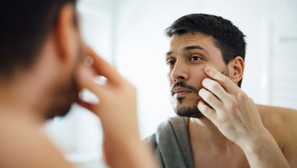 someone examining facial skin in bathroom mirror