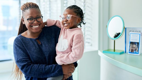 mother carrying daughter in eyeglass store