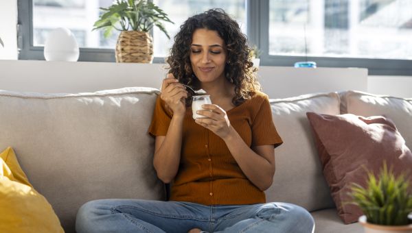 someone sitting on a couch and eating yogurt