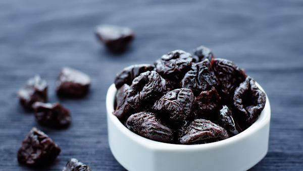 bowl of prunes on dark background