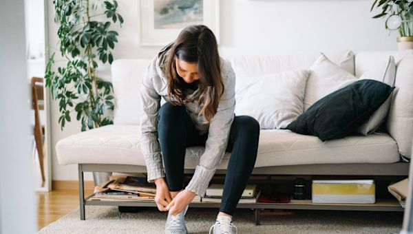 woman lacing up sneakers at home