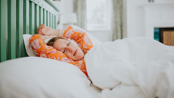 young woman happily sleeping in bed