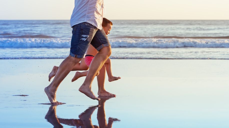 father and son running on the beach, barefoot