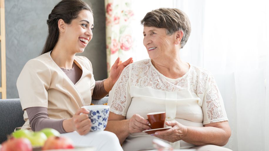 mature woman having tea with nurse
