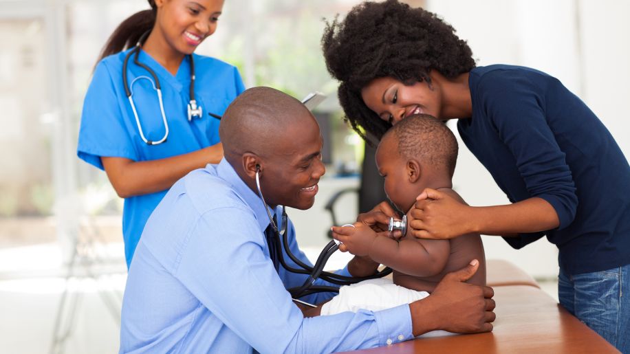 doctor checking the heartbeat of a happy baby