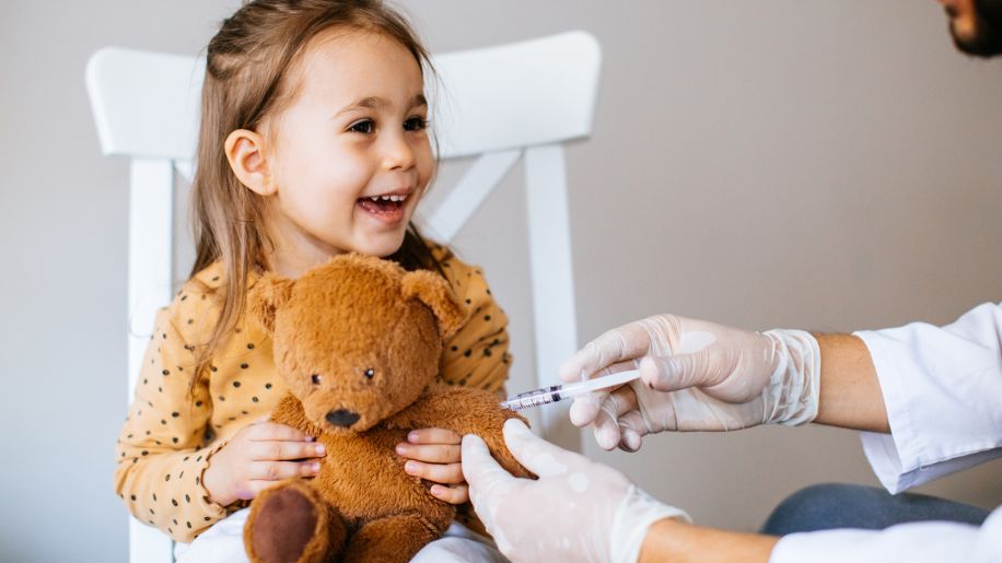 a doctor pretending to vaccinate a teddy bear
