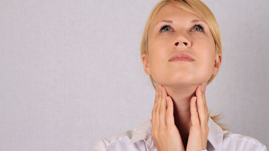 Woman feels for abnormal lumps on throat.