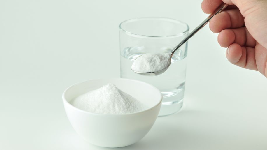 Hand spooning baking soda into a glass