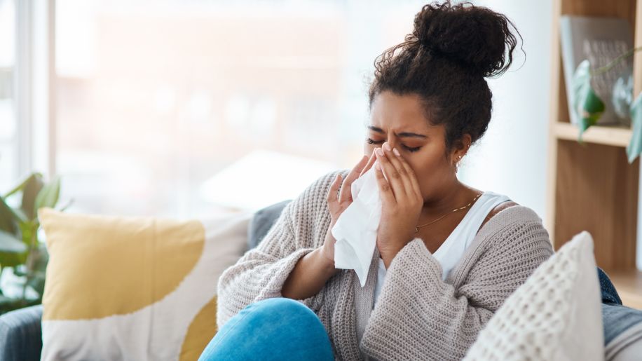 Woman sneezing on her couch