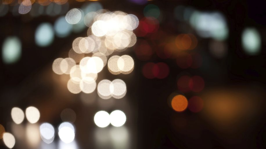 Blurry view of cars on a street at night.