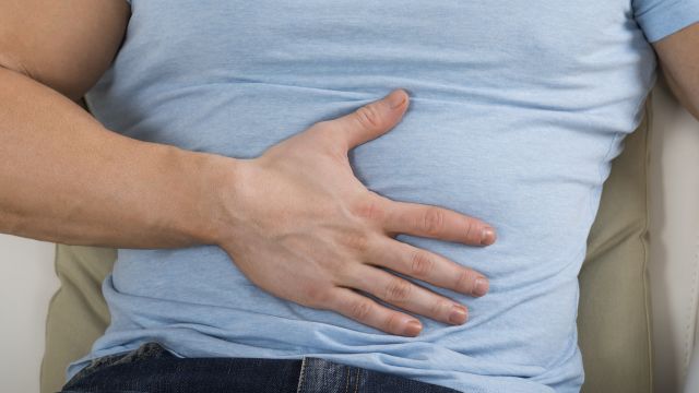 close up of man's hand on his stomach, blue t-shirt