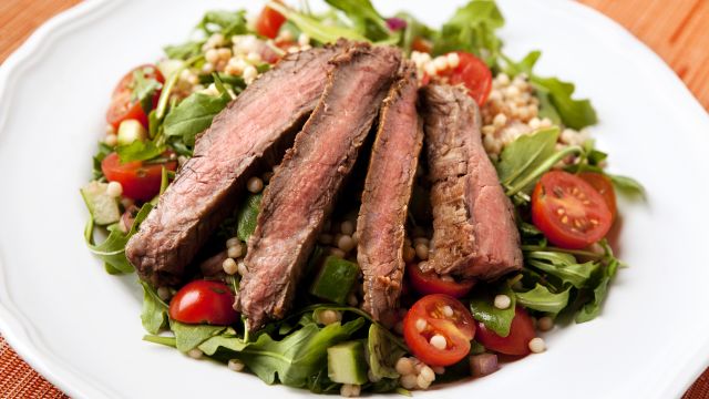 sliced steak on bed of lettuce with tomatos