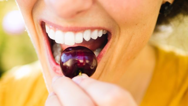 woman biting into cherry with teeth