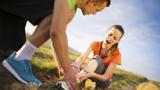 Injury - sports woman with twisted sprained getting help from man touching her ankle.