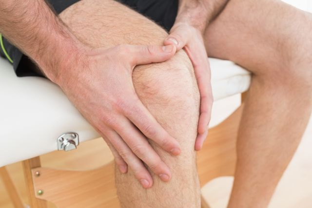 Close-up of the knee of a man experiencing psoriatic arthritis' early symptoms, like swelling, pain and tenderness. 