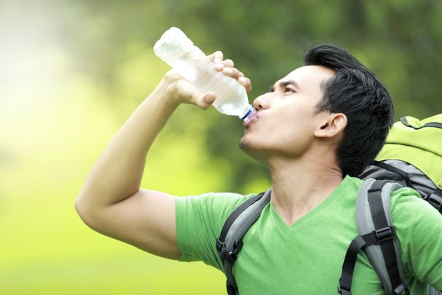 A man out hiking chugs a bottle of water—because drinking water does give you energy, while also quenching thirst.