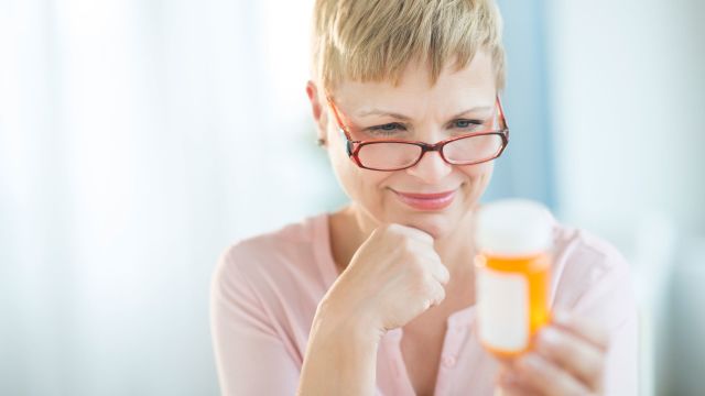 woman reading label on pill bottle