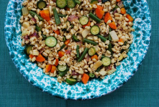 Summer whole barley salad with colorful vegetables in a green bowl