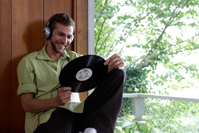 Man wearing headphones, holding long playing record