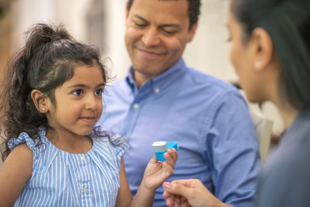 A young girl uses her inhaler for her childhood asthma symptoms.  