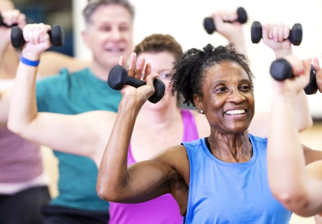 two senior women exercising outdoors with weights