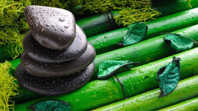 Smooth rocks sit on bamboo in a Zen garden, a relaxing place to practice fibromyalgia stress management and ease flare-ups. 