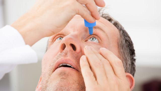 A man with red, burning itchy eyes uses OTC eye drops—it's just one of the simple home remedies for dry eyes.