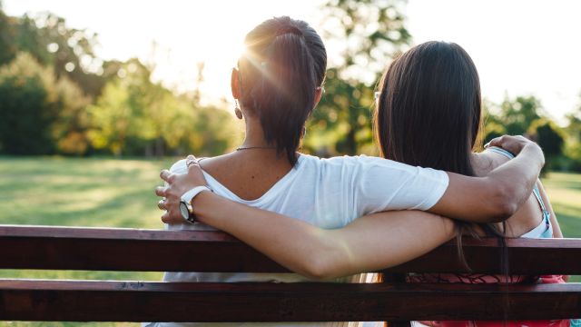 Two women with their arms around each other offer support—they're caring for cancer patients they love at home.