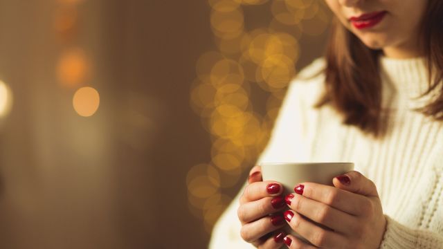 A pensive woman looks at her coffee wondering how to avoid relapse and stay sober. She is thinking about relapse prevention. 