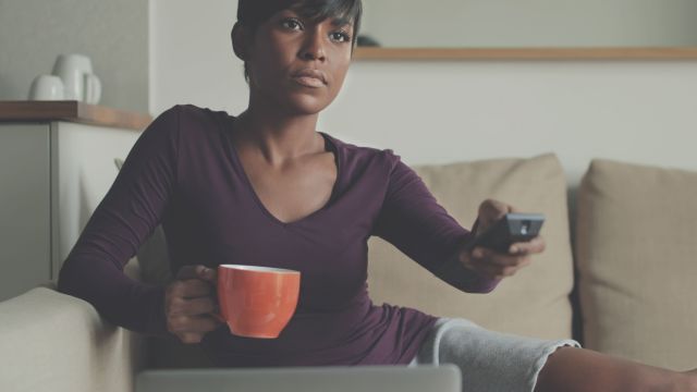 young black woman holding tv remote, young black woman watching television