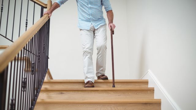 senior man walking downstairs with cane