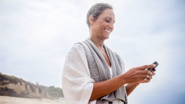 Woman using mobile phone on the beach
