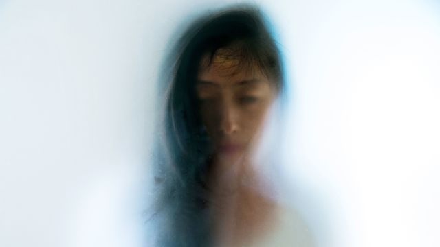Woman peering through frosted glass