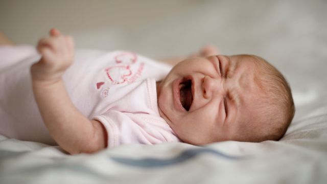 A newborn baby "crying it out" in the crib.