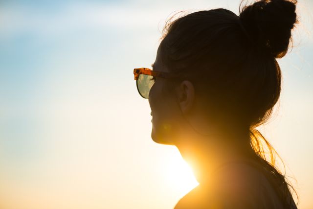 Young woman in sunglasses in sun rays outdoors