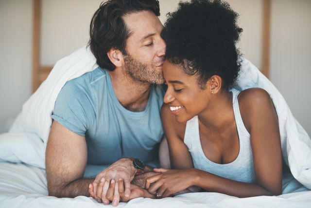 Happy young couple smiling in bed