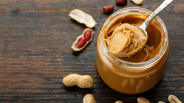 A spoonful of peanut butter in a jar.