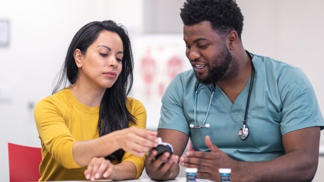 nurse helping patient with blood glucose meter