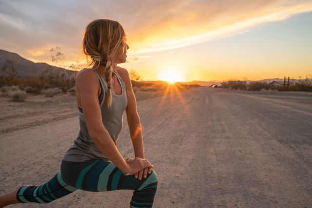 Fit woman stretching during sunrise