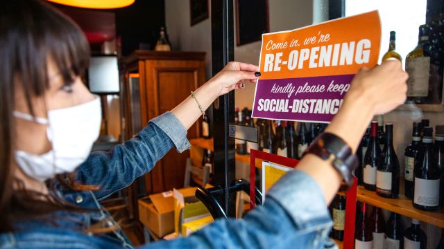 shop owner handing re-opening sign